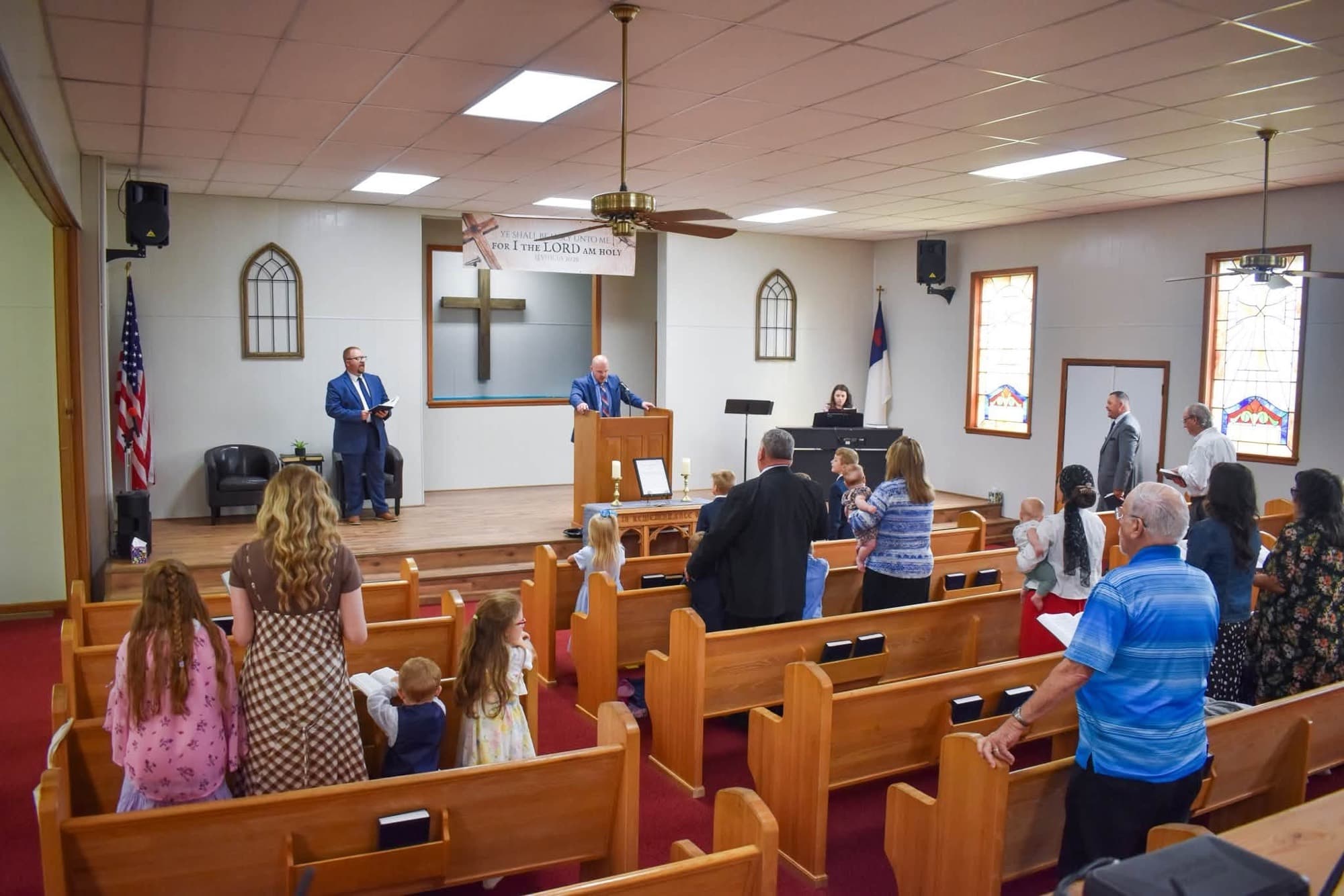 The congregation standing during the charter service while Pastor Brown preaches from the pulpit